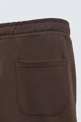 Pantalón jogger de corte relajado y pernera ancha, confeccionado en tejido de algodón con interior perchado. Cuenta con cintura elástica ajustable mediante cordón interior, bolsillos laterales y un bolsillo trasero de plastrón.
