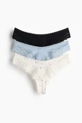 Pack de tres bombachas tipo Brazilian de tiro bajo, confeccionadas en punto de algodón y encaje. Incluye una de color negro liso, una celeste lisa y una de fondo crudo con estampado floreado pequeño. Todas cuentan con cintura en V con detalle de pequeño lazo en el centro y laterales de encaje.
