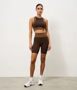 Bermuda deportiva Get Over de microfibra seamless, en color marrón con recortes contrastantes en tono tostado. Presenta cintura alta con pretina ancha cruzada y diseño ajustado.
