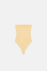 Body color amarillo pálido, estilo bandeau sin tirantes, con escote recto y cierre inferior a presión.