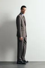 Blazer regular fit de Zara, confeccionada en tejido gris con mezcla de lana, con solapas de muesca, cierre de botonadura frontal y bolsillos con solapa en la cadera.