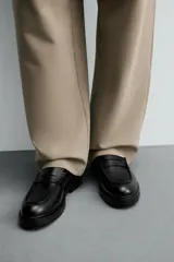 Mocasín de vestir negro con detalle de antifaz en la parte superior y suela track.