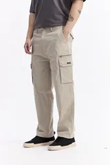 Pantalón cargo de corte baggy, color beige, con bolsillos laterales tipo cargo con cierre y solapa, y diseño de pierna ancha.