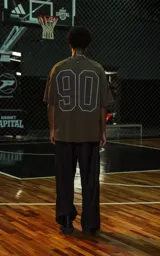 Remera de manga corta y cuello redondo, calce oversize, color marrón oscuro con efecto batik artesanal. Presenta un estampado frontal con la palabra "RAVERS" en tipografía universitaria con borde blanco.