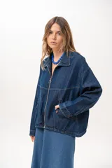 Campera de jean azul de silueta relajada, con cuello clásico, cierre frontal con cremallera metálica y bolsillos laterales.