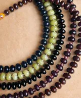 Collar compuesto por varias hileras de piedras naturales de calcedonia pulida en tonos verde, negro y bordó, con detalle de cuenta de cristal de Murano y cierre marinero con baño dorado.