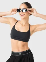 Top deportivo de bajo impacto color negro, con escote redondo y tirantes finos ajustables que se cruzan en la espalda. Cuenta con almohadillas removibles.