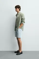 Bermuda de jean con corte regular fit, confeccionada en denim de algodón con elasticidad. Presenta diseño de cinco bolsillos, efecto lavado y cierre frontal con cremallera y botón.