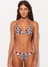 Conjunto de bikini Triya con estampado geométrico floral en tonos blanco, negro, fucsia y amarillo. El corpiño es de corte triangular con breteles finos y la bombacha es de corte clásico.