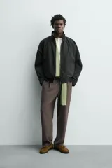 Cazadora bomber de corte relajado confeccionada en tejido técnico color negro. Presenta cuello subido, manga larga amplia, bolsillos de vivo en cadera, acabados elásticos y cierre frontal con cremallera de doble dirección.
