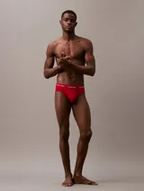 Pack de tres slips Calvin Klein de corte clásico, confeccionados en mezcla de algodón y elastano. Presentan cintura elástica con el logo de la marca y acabado que absorbe la humedad. El set incluye un slip negro, uno gris y uno rojo.