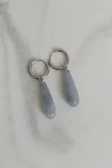 Aros tipo argolla de acero quirúrgico con dije colgante en forma de gota de piedra natural en tono marrón.