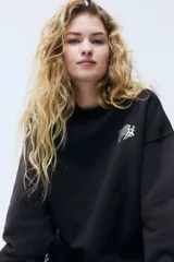 Buzo de corte oversized con interior cepillado, cuello redondo, hombros caídos y puños acanalados. Presenta un diseño estampado en el pecho con la inscripción Sport Club.