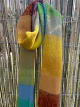 Bufanda larga con flecos, diseño a cuadros en tonos amarillos, naranjas, azules y celestes.