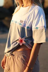 Remerón gris con mangas cortas y estampado frontal con el logo de la marca 'Glassy Waves' y un diseño de ondas y motivos tribales.