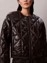Campera acolchada Calvin Klein de color negro, con diseño matelasseado con monogramas, cuello redondo y cierre frontal de cremallera.