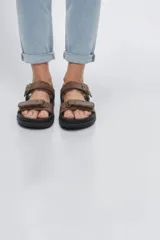 Sandalias negras de tiras ajustables con cierre de velcro, suela plana y diseño cómodo para uso diario.