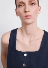 Top de denim color azul oscuro, con escote cuadrado, sin mangas y cierre frontal con botones.