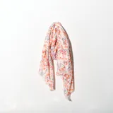 Pashmina estampada con flores en tonos naranja, rosa y violeta sobre fondo blanco.