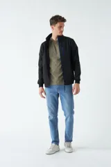 Campera softshell negra con cuello alto, cierre frontal con detalles en azul y bolsillos laterales con cierre. Es una prenda técnica diseñada para proteger del viento, la lluvia y el frío.