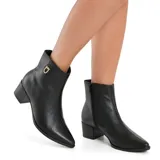 Bota corta de cuero negro con taco cuadrado y punta fina. Presenta un detalle metálico dorado con logo en el lateral superior y cierre lateral.