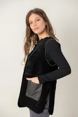 Chaleco de cuero negro con diseño sin mangas, corte recto y bolsillos frontales con contraste de textura. Presenta costuras visibles y un acabado artesanal.