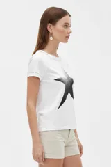 Remera negra de manga corta, con cuello redondo y ajuste al cuerpo. Cuenta con un gran estampado floral en tono gris en el frente y detalle de tachas plateadas alrededor del cuello y en los puños.