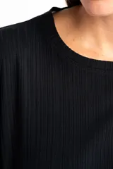 Remera de corte oversize, confeccionada en tejido de viscosa con textura acanalada, de color negro, con mangas cortas y cuello redondo.