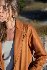 Blazer de cuero color celeste metalizado, con solapas, cierre con broches tipo tanca de madera y puños con detalle de piel sintética marrón.