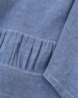 Blusa de lino color azul jean, con cuello redondo, mangas amplias tres cuartos y detalle de volado fruncido en el ruedo.