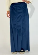 Pollera larga azul de terciopelo con corte recto y paneles verticales.