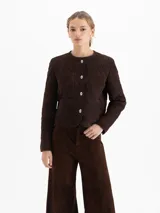 Chaqueta de cuero gamuzado color marrón con diseño matelaseado en toda la prenda. Presenta cuello redondo, cierre frontal con botones metálicos y cuatro bolsillos delanteros.