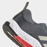 Championes de training Adidas modelo Everyset en color gris con detalles en blanco y rojo. Presentan una parte superior de tejido transpirable, mediasuela de EVA de doble densidad para estabilidad y confort, y suela de caucho con tracción multidireccional.