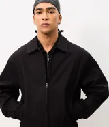 Campera boxy de poliéster color beige, con cuello inglés, cierre frontal de cremallera, mangas largas con elástico en los puños, bolsillos laterales y detalles de recortes.