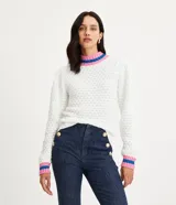 Suéter de punto blanco con cuello alto y puños acanalados con rayas horizontales rosas y azules.