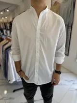 Camisa blanca de manga larga con cuello mao y cierre frontal de botones, diseñada con un corte clásico.