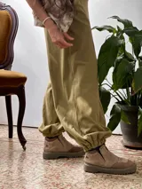 Conjunto compuesto por una remera de cuello redondo y un pantalón tipo balloon de tiro alto con puños elásticos en los tobillos y bolsillos laterales. Ambas prendas están confeccionadas en rib de algodón color verde oliva.