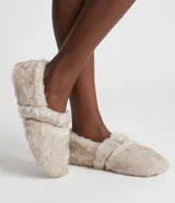 Pantuflas cerradas tipo zapatilla de color beige, confeccionadas en poliéster con revestimiento de felpa suave y suela flexible.