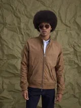 Campera tipo bomber color marrón, confeccionada en tela encerada, con cierre frontal, cuello tipo mao y puños y ruedo acanalados.
