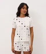 Blusa de pijama de manga corta con cuello redondo, confeccionada en tejido suave con estampa de corazones en tonos neutros.