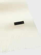 Bufanda de punto Raschel color blanco hueso, con diseño liso y terminación en flecos cortos. Incluye una pequeña etiqueta metálica con el logo de la marca.
