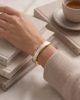Pulsera esclava rígida de plata 925 y lámina de oro 18k, con banda central texturizada en tono blanco con acabado brillante.