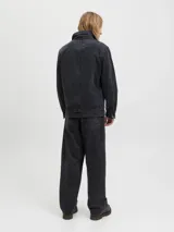Pantalón de corte baggy y tiro alto, confeccionado en denim con efecto lavado ácido en color negro. Presenta una silueta amplia y relajada, con bolsillos funcionales y cierre frontal.