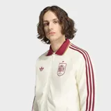 Campera deportiva Adidas Originals de la selección de España, color blanco con detalles en bordó. Presenta cuello tipo polo, cierre frontal con cremallera, las icónicas tres tiras en las mangas y el escudo de la selección junto al logo del trébol en el pecho.