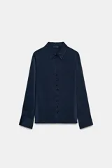 Camisa de cuello solapa y manga larga, confeccionada en tejido satinado azul marino. Presenta cierre frontal con botones forrados a tono y puños rectos.