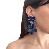 Aros colgantes con forma de dos flores superpuestas, hechas de resina marmolada en tonos azul y blanco.