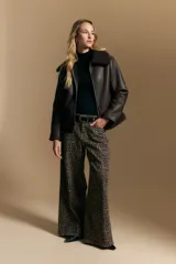 Campera tipo gamulán de cuero sintético negro, con interior y detalles de corderito sintético al tono en cuello y ruedo. Presenta cierre frontal metálico y diseño de silueta relajada.