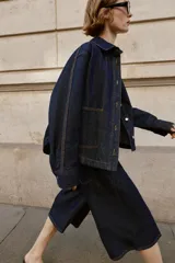 Bermuda de tiro alto confeccionada en denim azul oscuro, con diseño de pernera ancha, cinco bolsillos y cierre frontal con cremallera y botón.