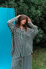 Conjunto de camisa y pantalón de fibrana con diseño a rayas verticales en tonos verde, blanco, violeta y negro. La camisa es de corte amplio con bolsillos frontales en el pecho, y el pantalón es de corte recto y holgado.
