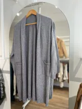 Saco largo de tejido de punto color gris, con bolsillos laterales y corte italiano.